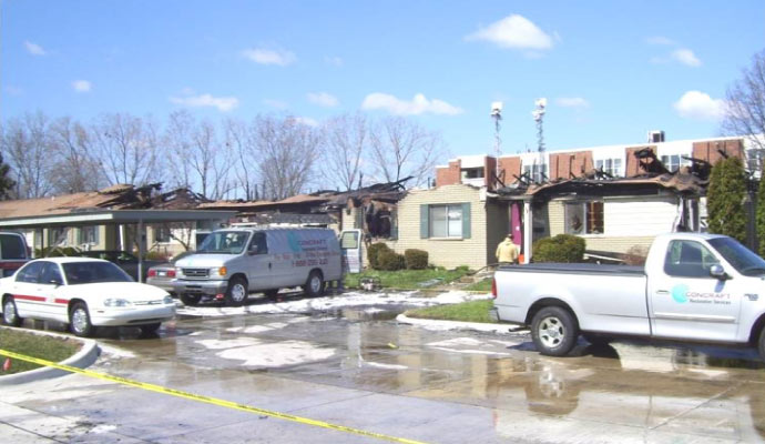 damaged building with fire trucks and service vehicles after a fire