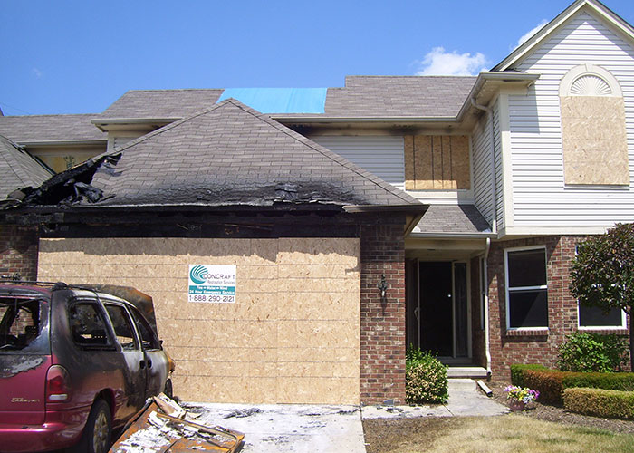 a partially fire damaged house roof and a car