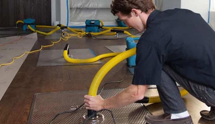 Expert drying water-damaged floor with specialized equipment.