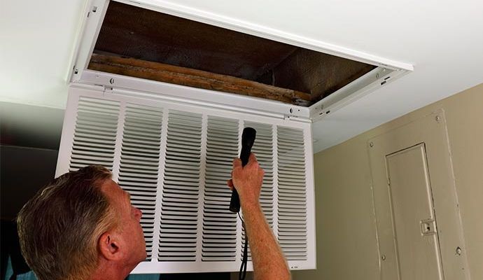Technician inspecting damaged duct Technician inspecting a damaged HVAC duct system