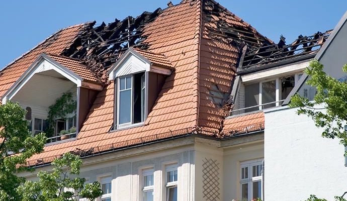Fire-damaged house with visible structural damage Exterior of a house showing severe structural damage from fire