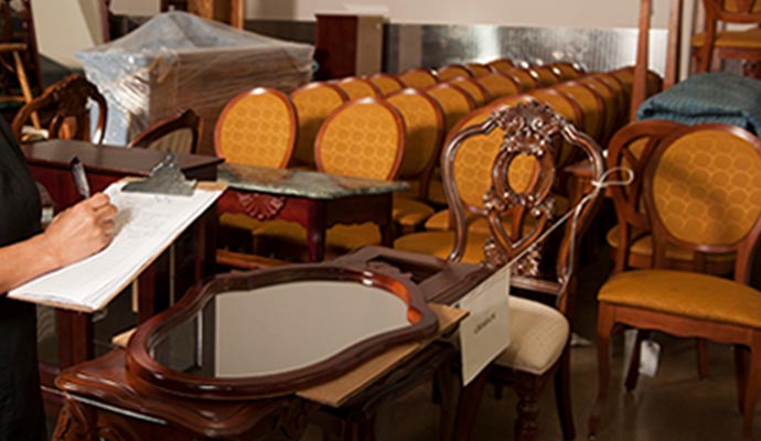 A person inspecting furniture inside a storage unit A person inspecting furniture inside a storage unit