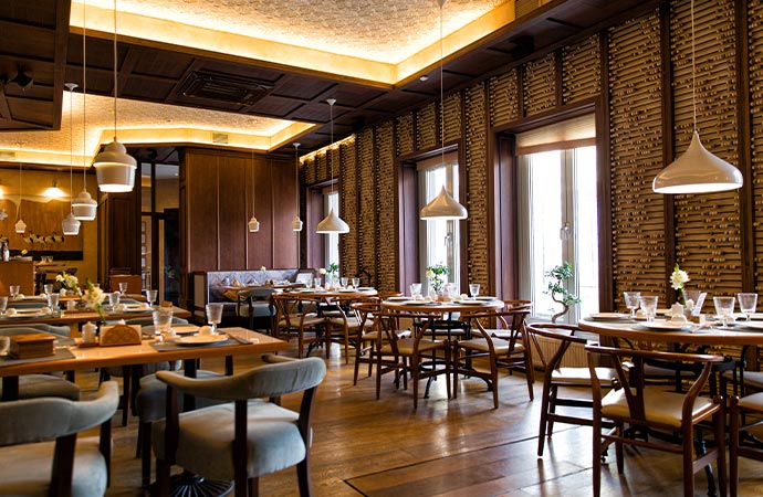 an interior view of a clean restaurant with multiple wooden tables with set of plate and glass