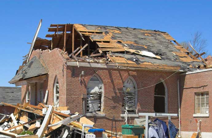 a damaged white house with its roof partially damaged by stroms