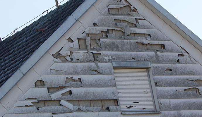Hail damaged house siding House siding damaged by hail, showing dents and broken exterior surfaces