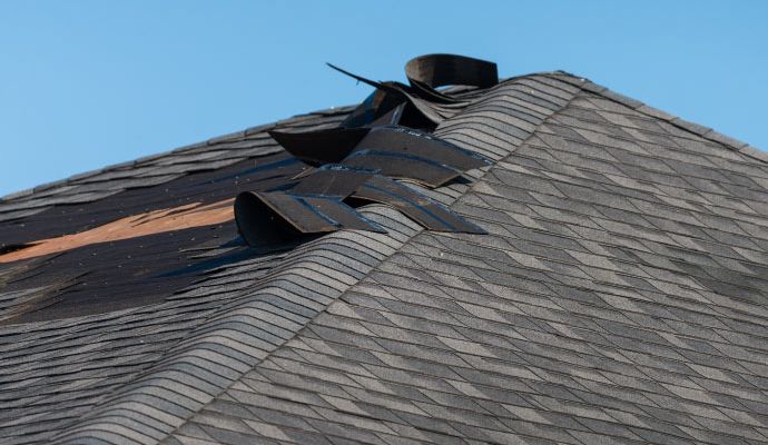 Visible shingle damage on house roof Residential roof with visible shingle damage