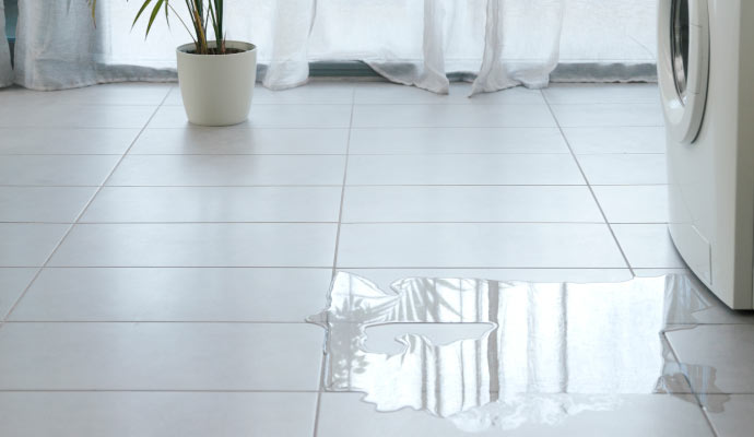 A leaking washing machine flooding the tile floor